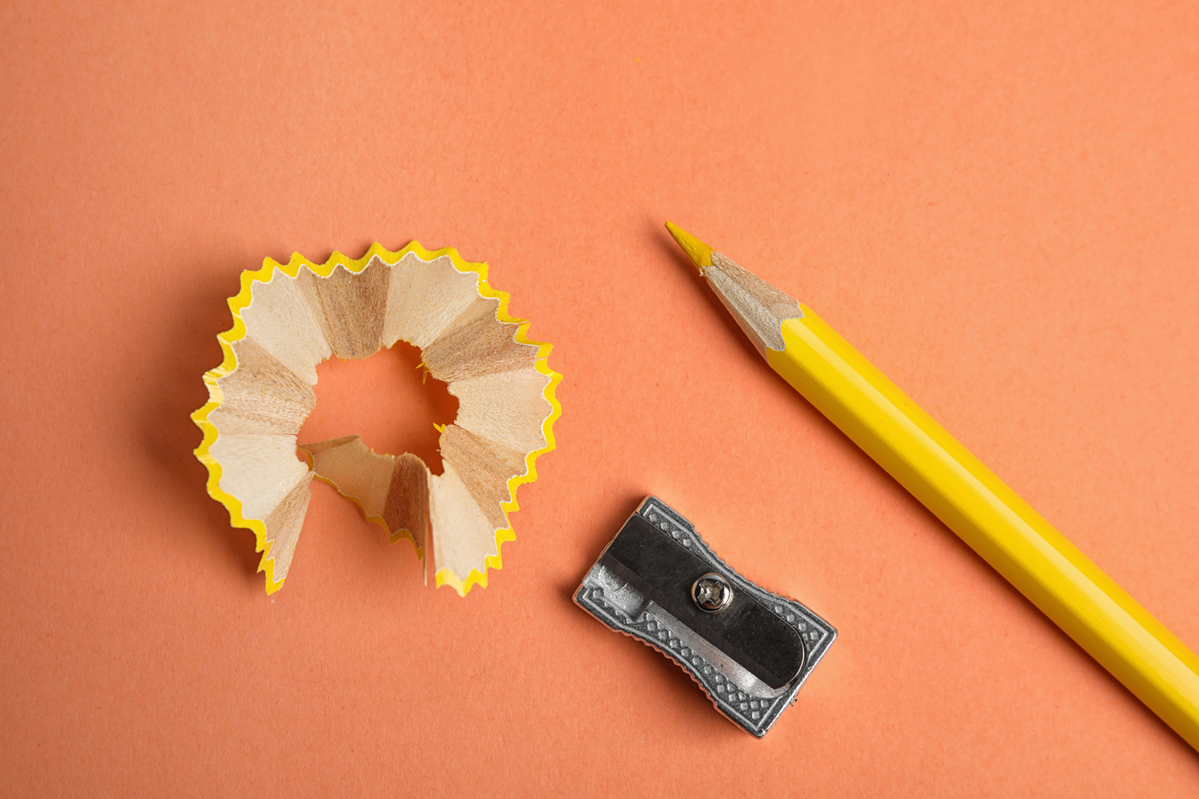 Color Pencil, Sharpener and Shavings on Orange Background, Flat Lay